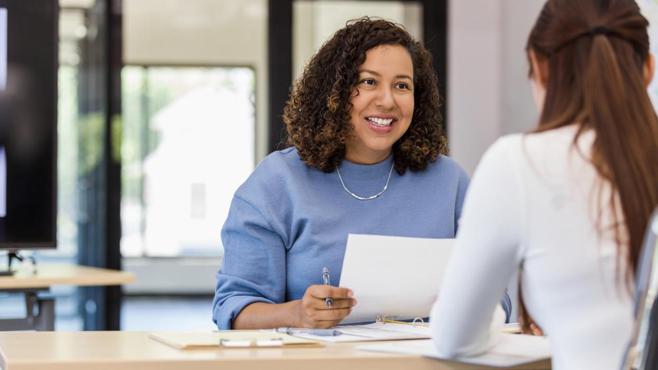 A smiling Flexible Benefits Coordinator dicusses options with a new employee.