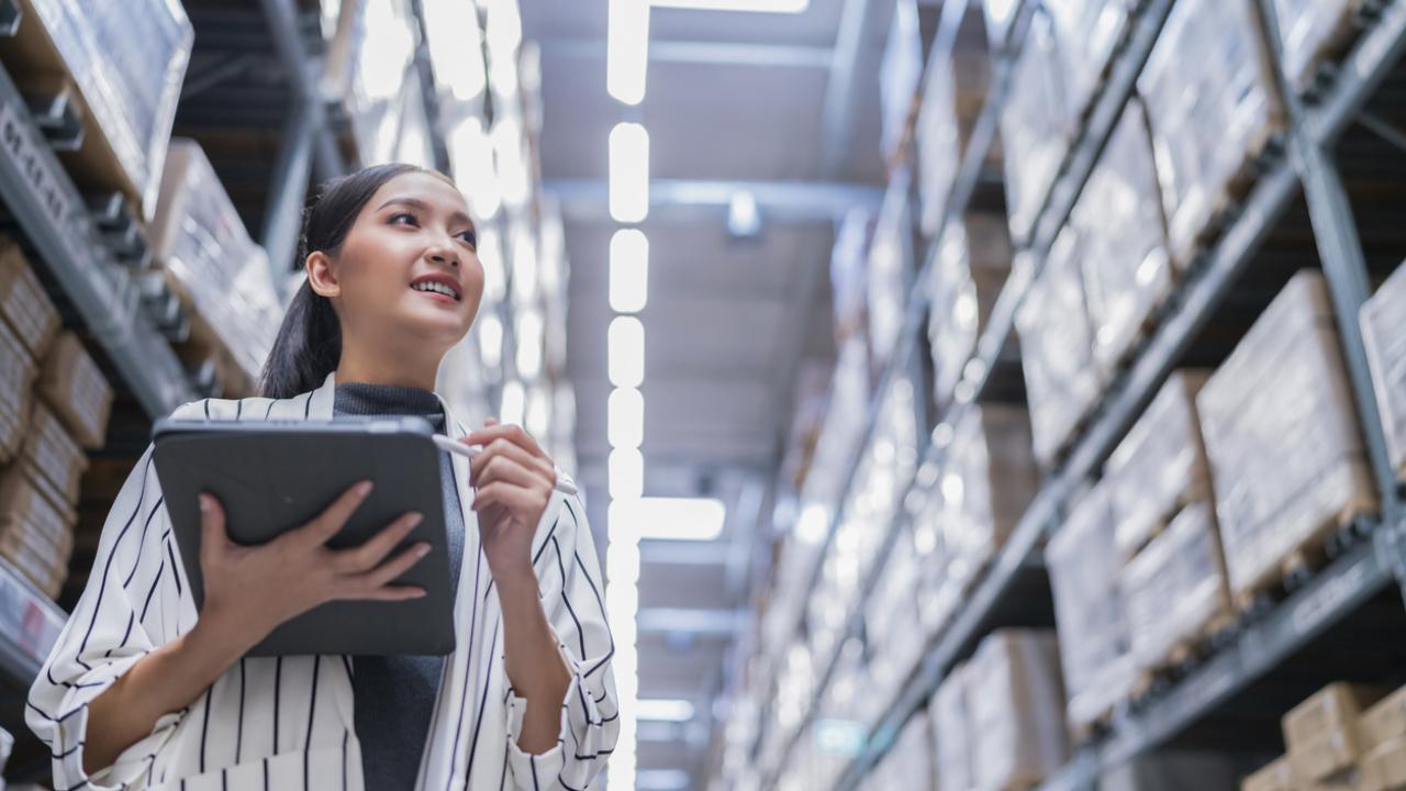 A supplier walks through a warehouse, reviewing inventory.