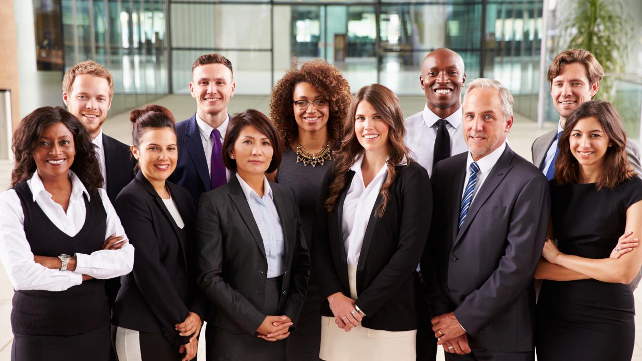 A smiling group of people dressed in work attire.