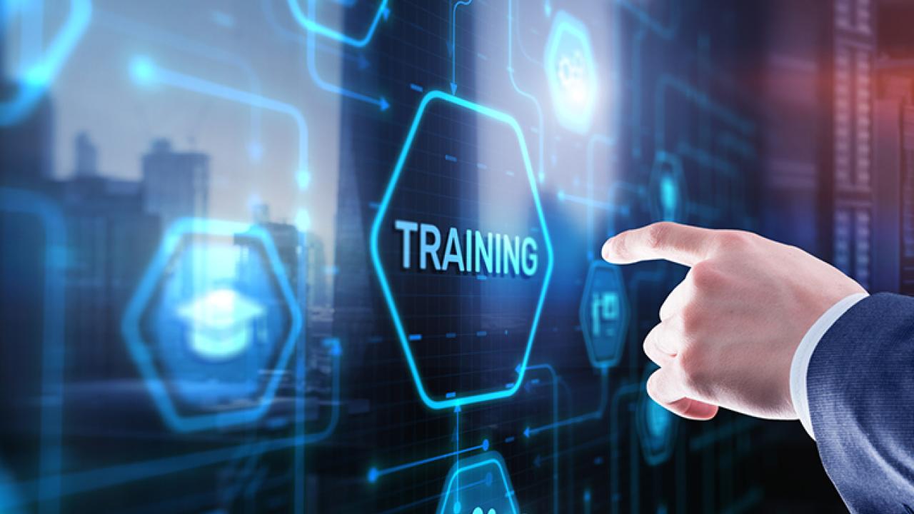 A hand points to an icon labeled "Training" on a computer projection.