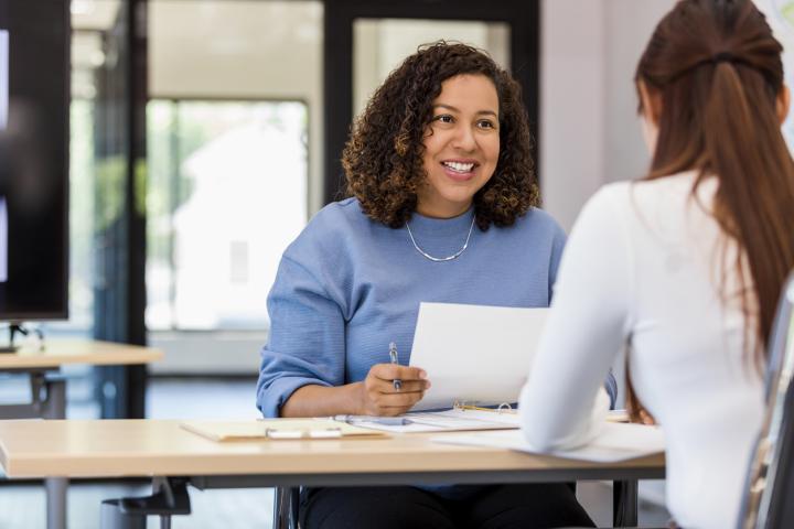 HR professional sits at a desk, explaining flexible benefits to an employee.