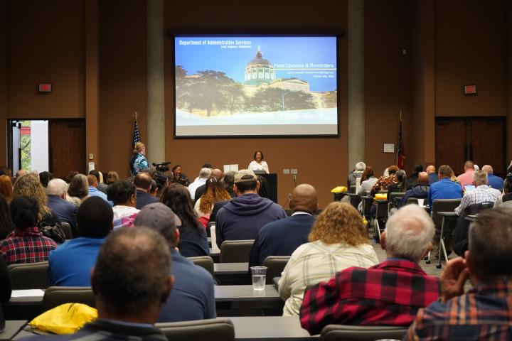 Photo depicts individuals at Fleet Day 2025 listening to the speaker. Photo is shot from the back of the room and shows a vast number of attendee's 