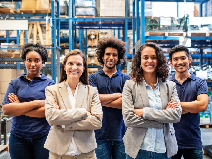 A group of five people stand in a warehouse, looking happy.
